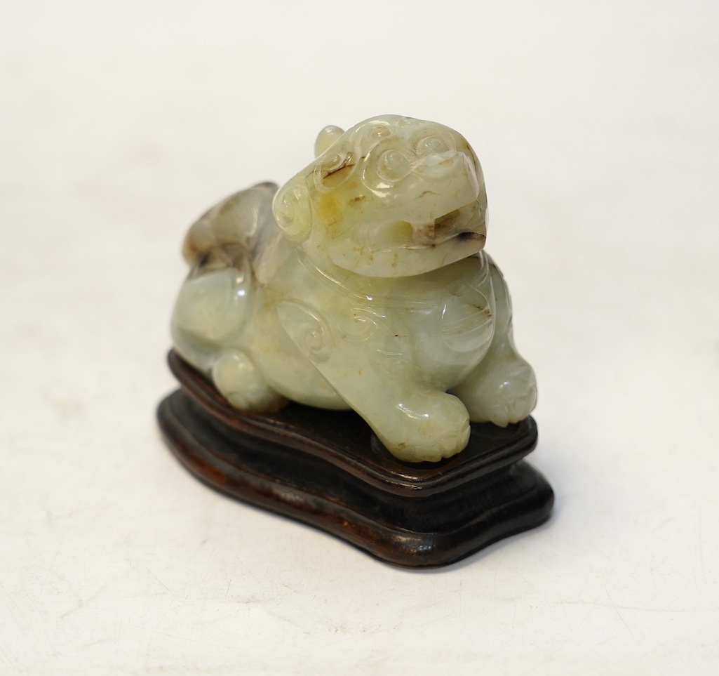 A Chinese carved jade ‘lion dog’ and stand, 8cm tall. Condition fair to good.